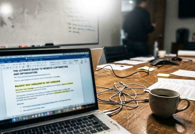 Conference room meeting setup with an unposed a laptop open to a draft titled “The